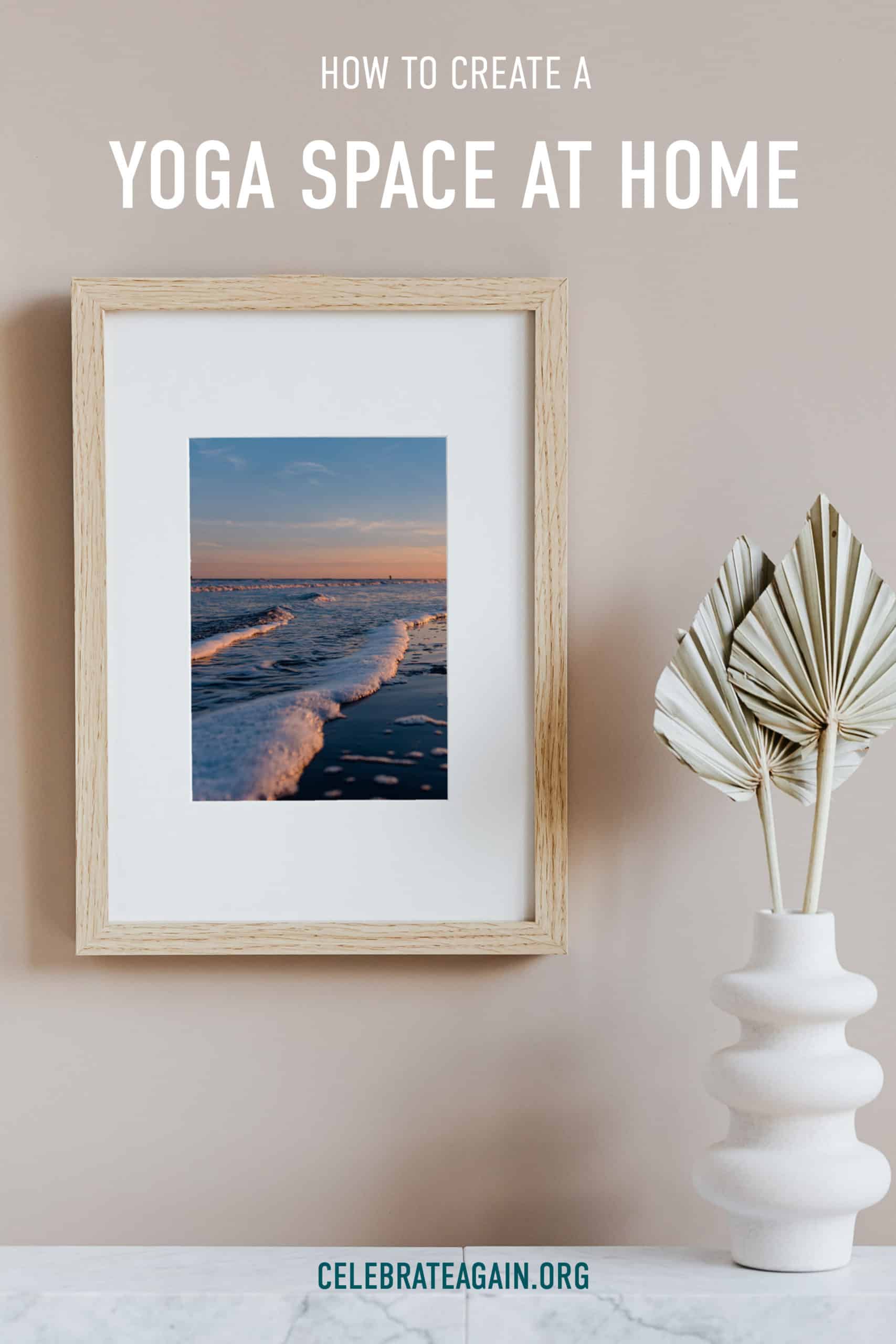 how to create a yoga space at home text photo by Celebrate Again of ocean waves at sunset hanging on a wall in a wooden frame next to a paper plant decor for a yoga space at home