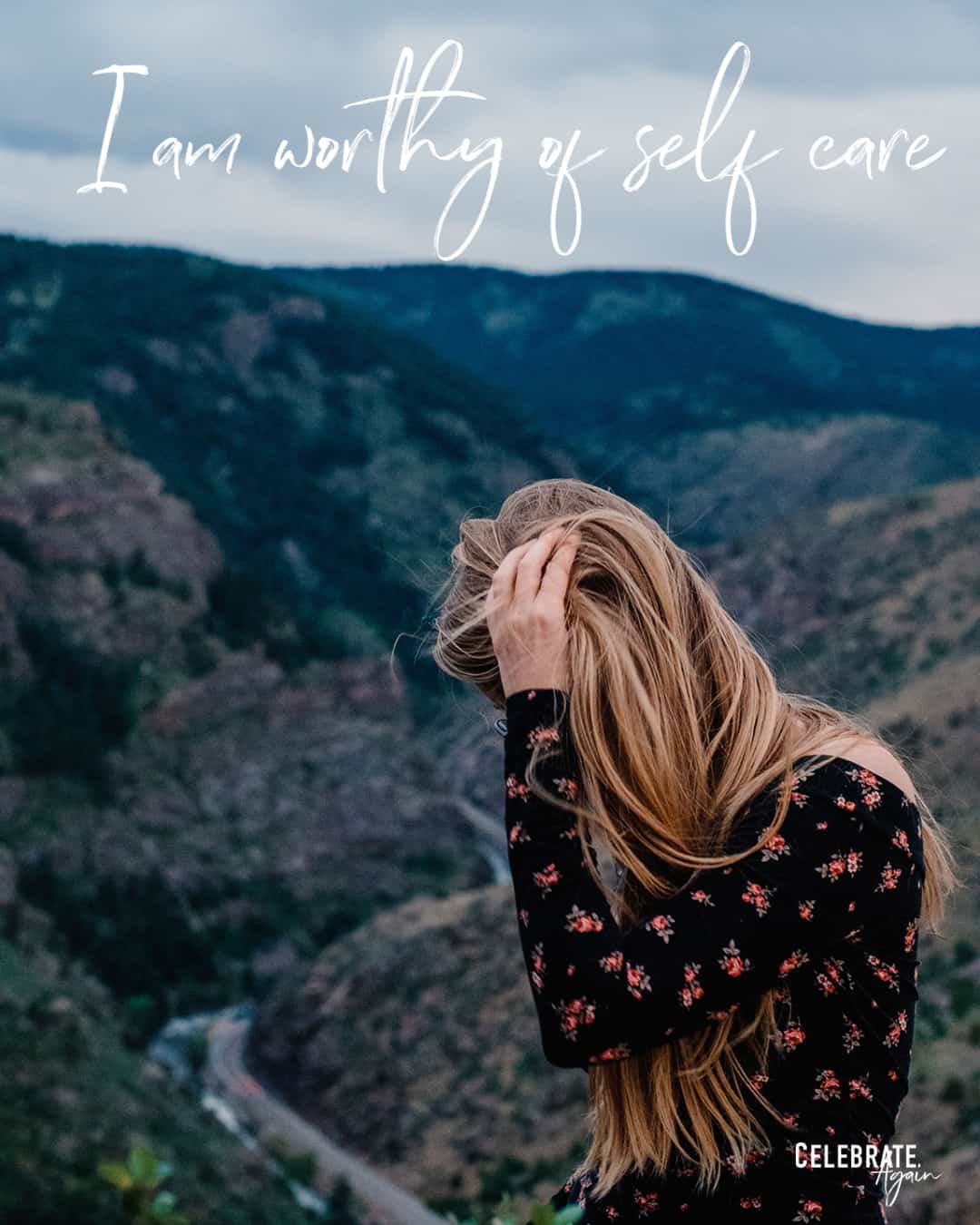 "I am worthy of self care" as a mom quote by Celebrate Again view of a woman pulling her hair back on the top of a mountain cliff