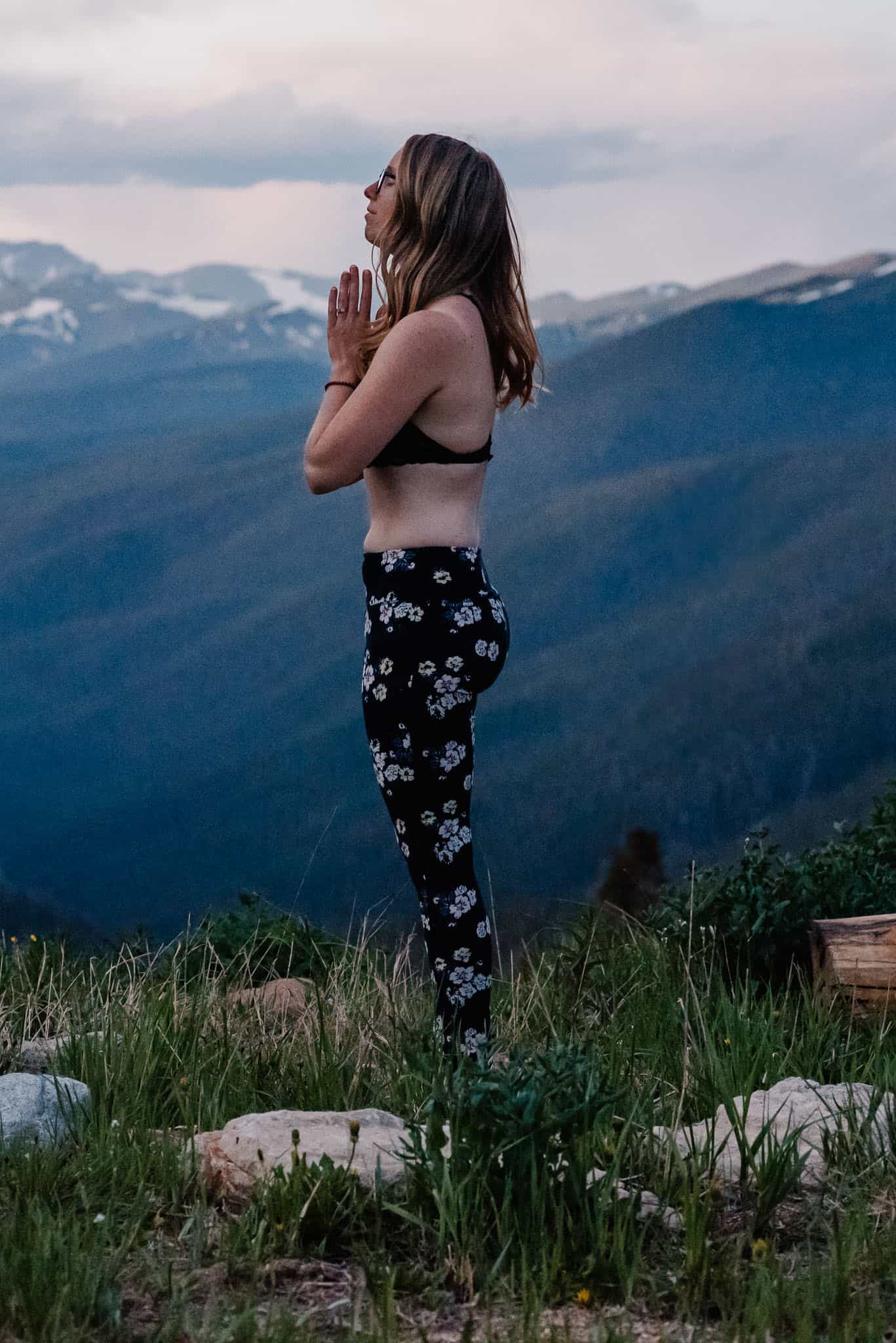 Emmy in namaste mudra doing yoga for wrists in mountain pose on top of a mountain