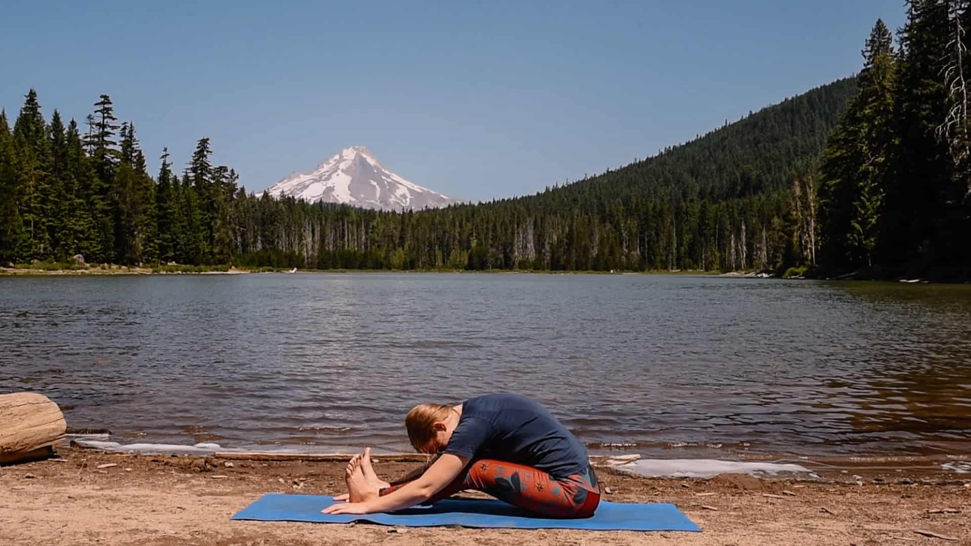 Emmy doing forward fold near an alpine lake for yoga to feel your best