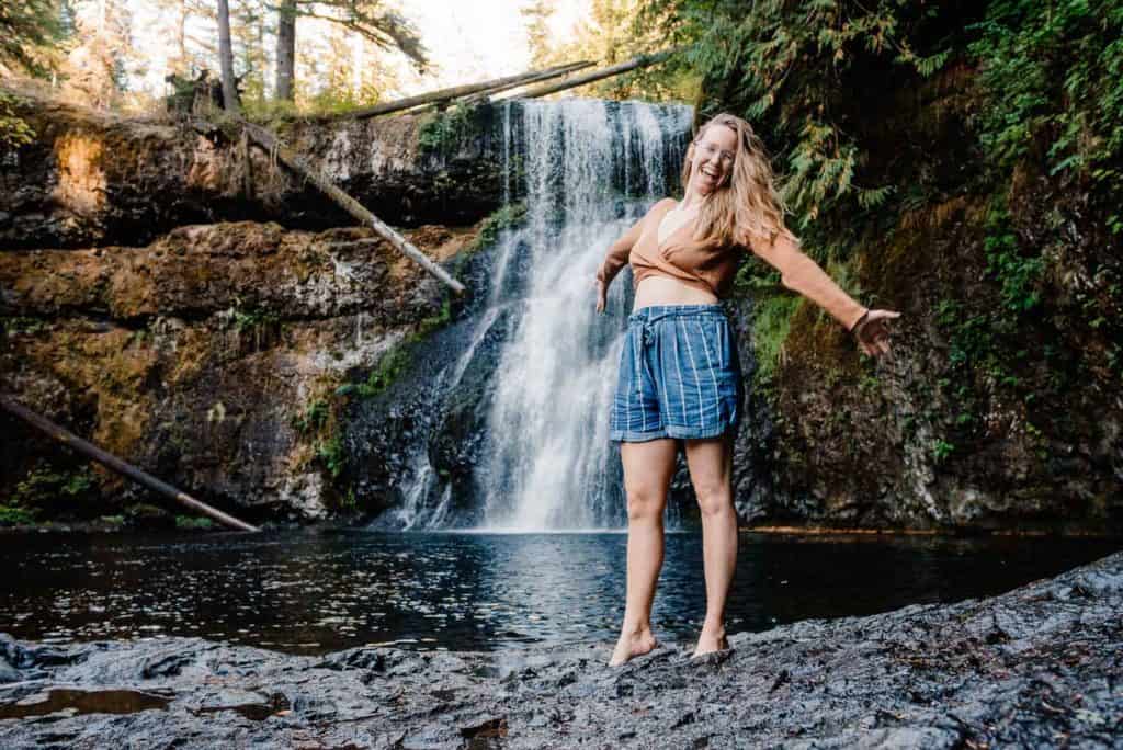 Lumalia near a waterfall with her arms out stretched